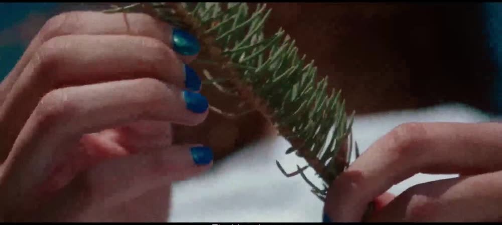 Blue fingertips meet a branch in the fashion film
